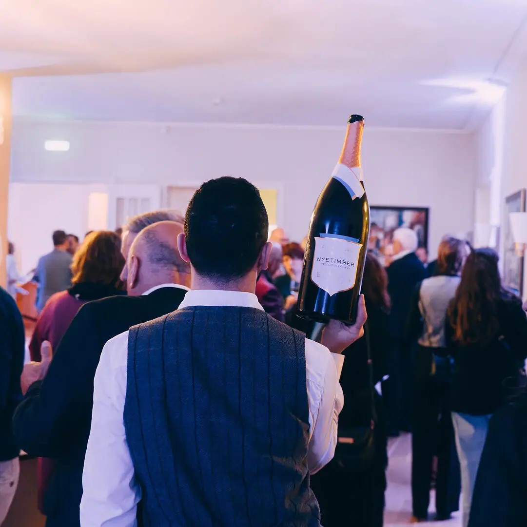 A man holding a bottle of wine indoors.