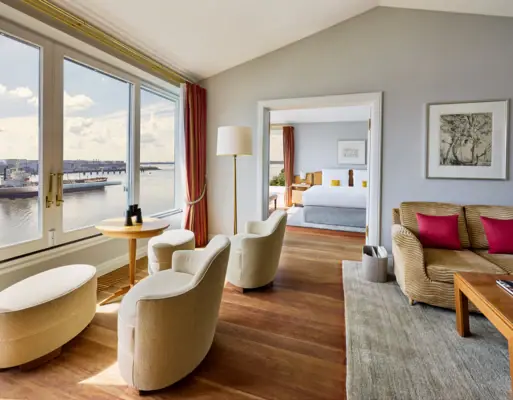Rooms & Suites A room with a view of the water and a bed in the foreground.